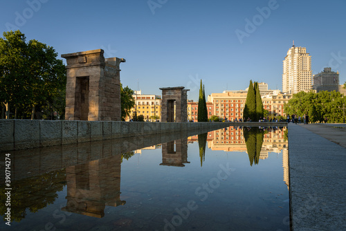 The Egyptian Temple of Debod and the surrounding buildings reflected in the waters of the pond on a spring afternoon, Madrid, Spain