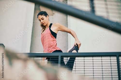 Fit female runner stretching her leg before running.