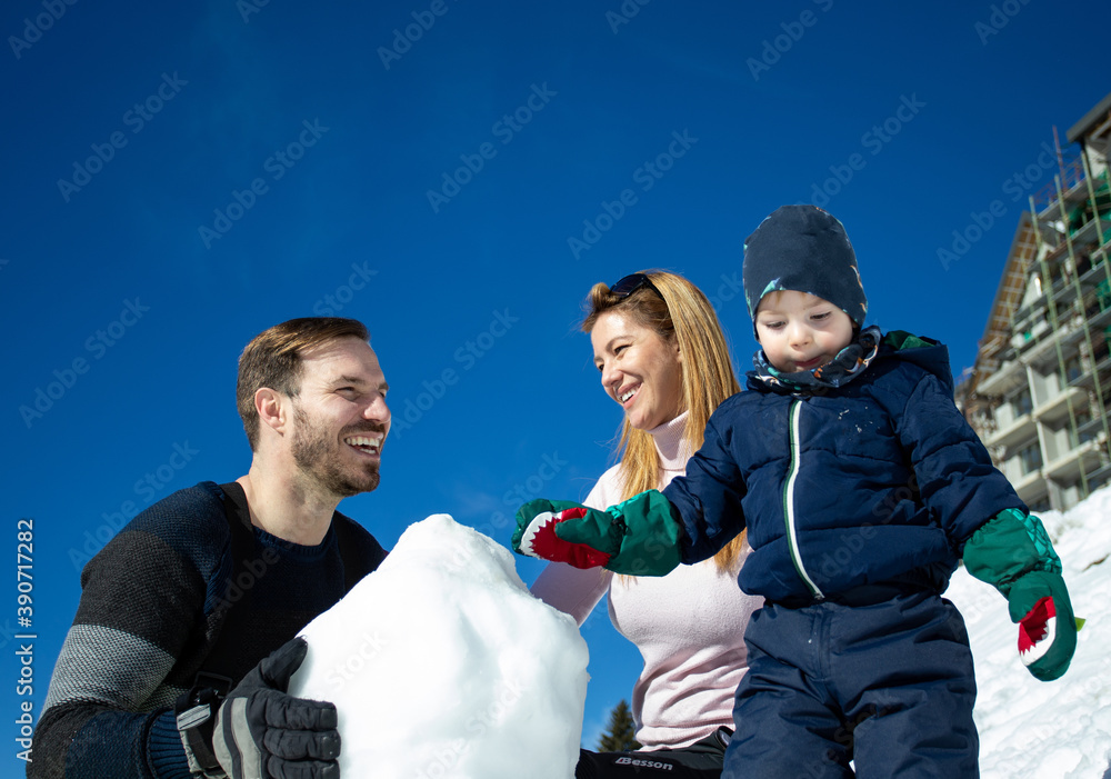 Obraz premium Parents with boy making snowman on mountain