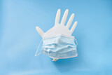 Isolated glove and face mask on a blue background. Stop corona virus