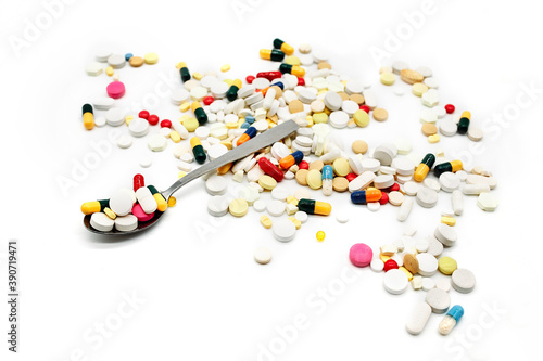 Spoon full of colourful pills and medicines isolated in white background