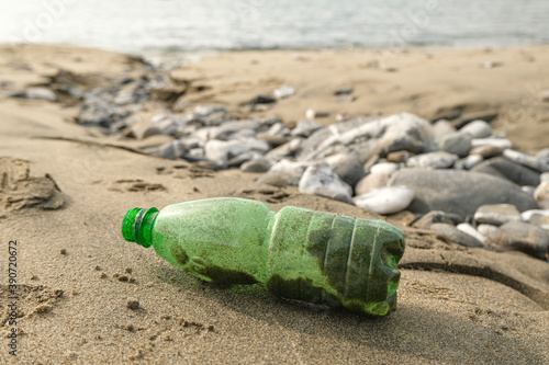 Green Plastic bottle trash abbandoned on sea coast ecosystem,environmental pollution issues