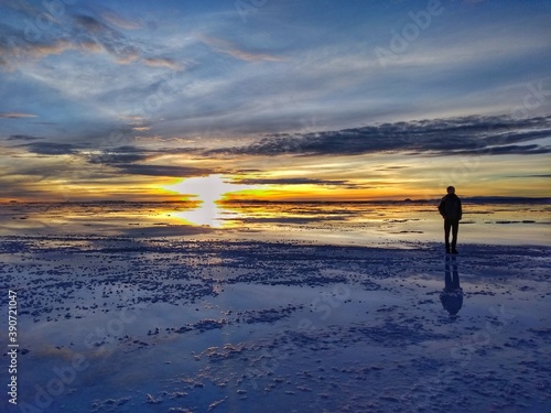Man - Sunrise - Salar de Uyuni  the largest salt flat in the world  Bolivia  South America. During the rainy season  a thin layer of water transforms the flats into a mirror reflection of the sky.