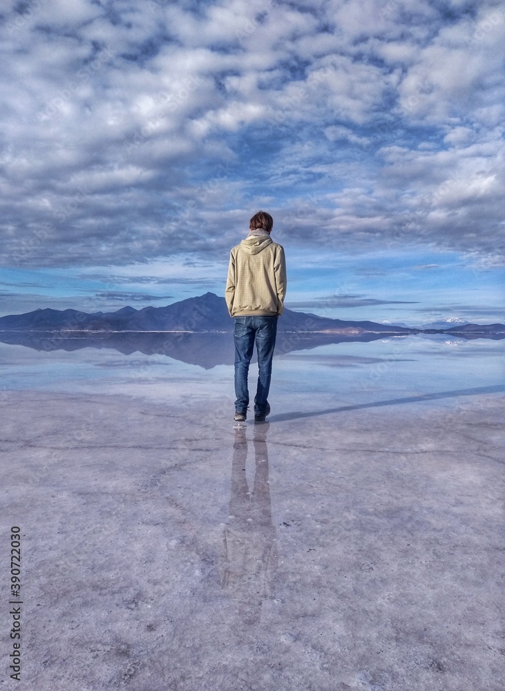 Man - Salar de Uyuni, the largest salt flat in the world, Bolivia, South America. During the rainy season, a thin layer of water transforms the flats into a stunning mirror reflection of the sky.