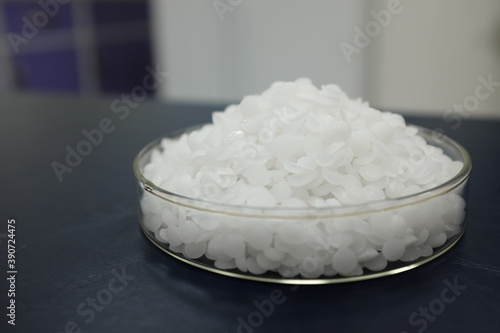 Obraz na płótnie Selective focus of sodium or potassium hydroxide white chemical compound pellets or prills in a petri dish in black background. w salonie
