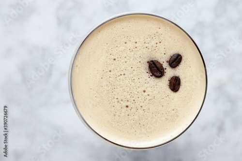 Top view of an Espresso Martini garnished with three coffee beans on a marble table