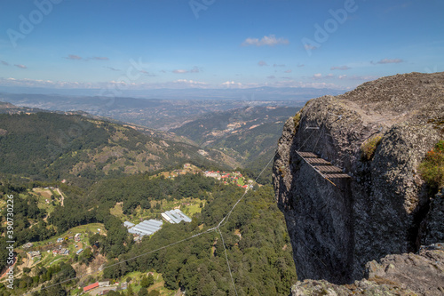 Vertical shot of a female rock climber on a mountain with a small village in the background