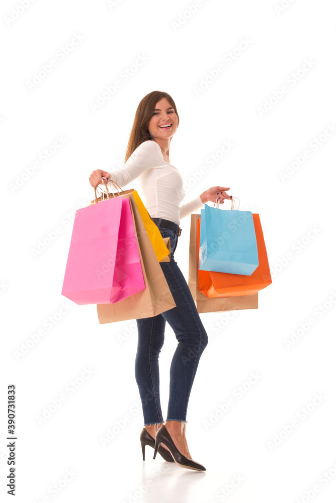 Beautiful girl smiles and holds purchases in her hands. Brunette stands on a white background and smiles after a successful shopping. 