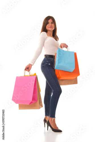 Beautiful girl smiles and holds purchases in her hands. Young girl with purchases in her hands posing at the camera. 