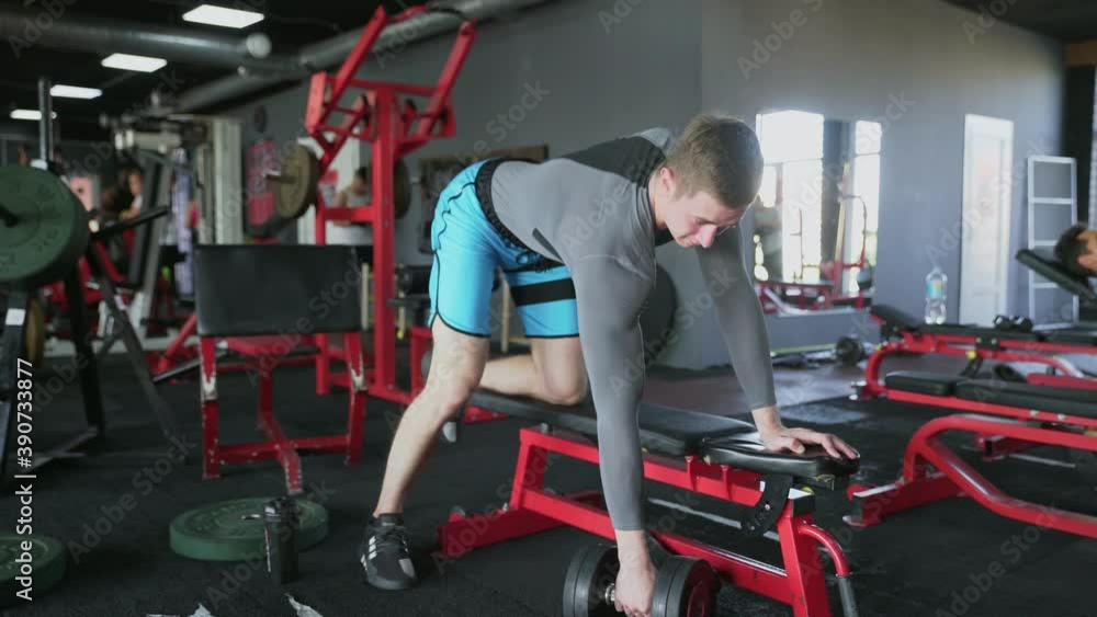 Handsome athletic man performing One-arm dumbbell row at gym Handsome athletic man performing One-arm dumbbell row at gym