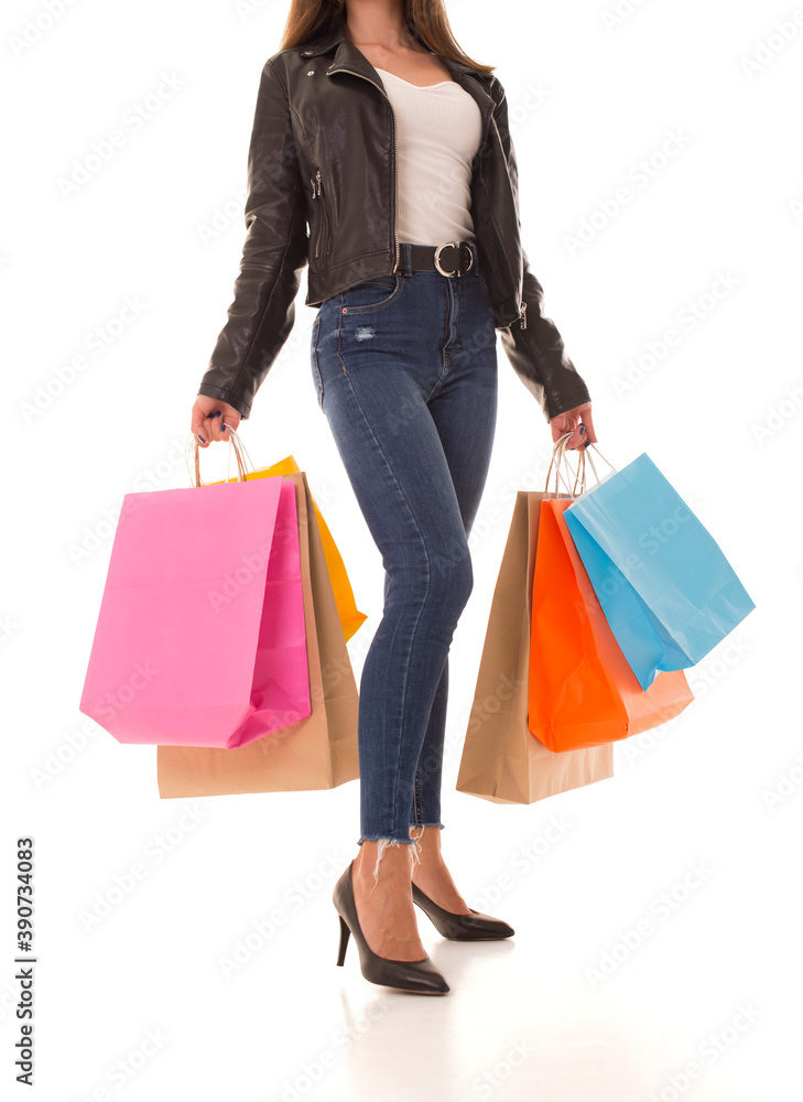 Girl with purchases in her hands stands on a white background. Young girl in high heels after shopping. Girl with purchases in her hands stands on a white background. Young girl in high heels after shopping.