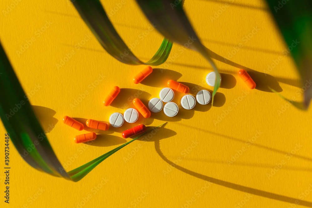 different pills, tablets or capsules in on yellow background close-up top view flat lay. Concept of modern medical treatment, pharmacy, healthcare. Abstract composition with plant leaves different pills, tablets or capsules in on yellow background close-up top view flat lay. Concept of modern medical treatment, pharmacy, healthcare. Abstract composition with plant leaves
