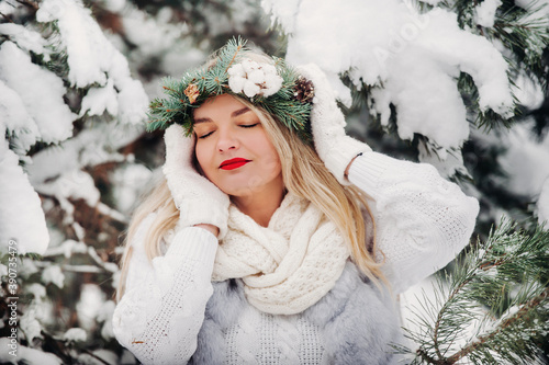 Portrait of a woman in white clothes in a cold winter forest. Girl with a wreath on her head in a snow-covered winter forest photo