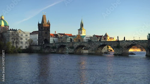 moving shot of the view of charles bridge and flowing river vltava in the center of prague at sunset the sky is blue in czech republic