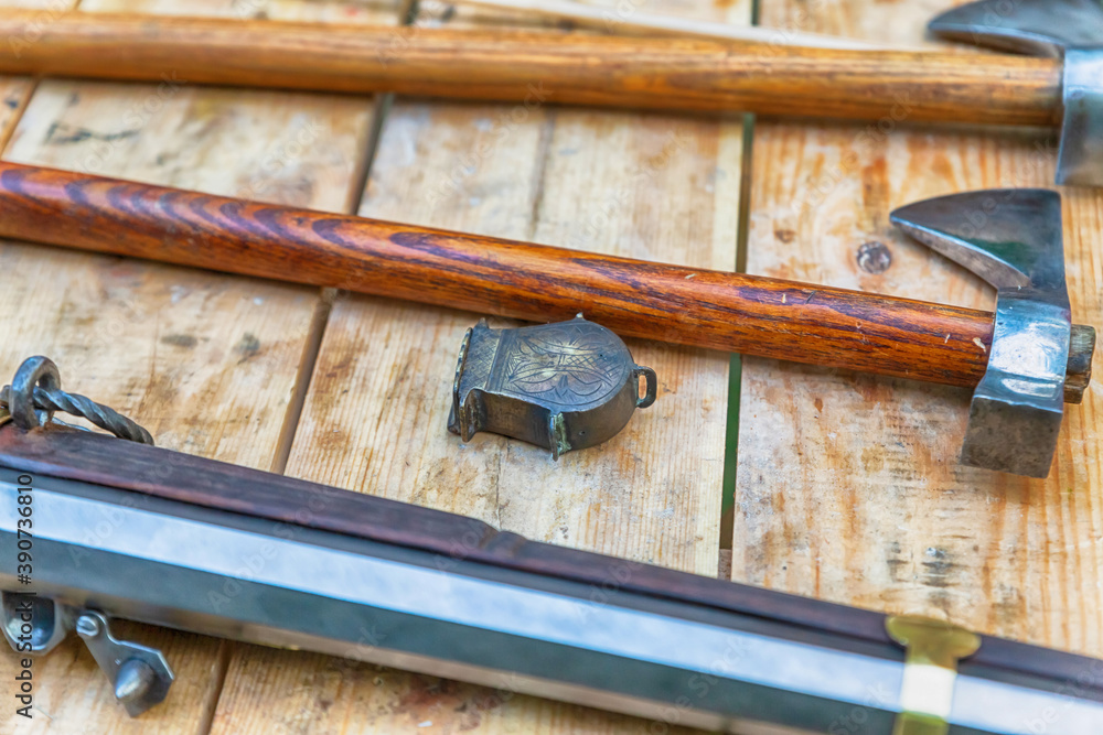 battle ax with a smooth wooden handle, a musket and a powder flask on a wooden table battle ax with a smooth wooden handle, a musket and a powder flask on a wooden table
