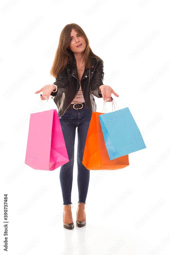 Girl with open mouth stands on a white background and holds packages. Surprised brunette with new purchases after sale. 