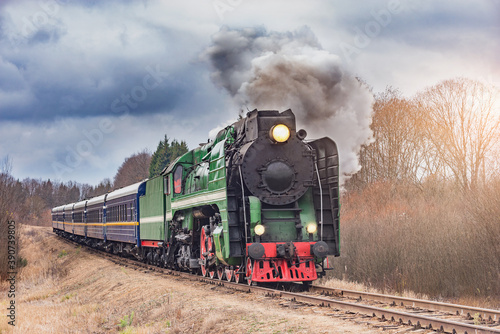 Steam train moves at autumn day time.