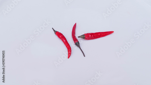 Three bright red chili peppers on white background. Space for text. Design concept.