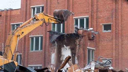 Obraz na plátne a large excavator breaks down the house, demolishing a building in the city