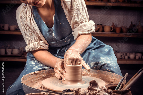 Craftsman siting on bench with pottery wheel and making clay pot. Handicraft production. Close-up. photo