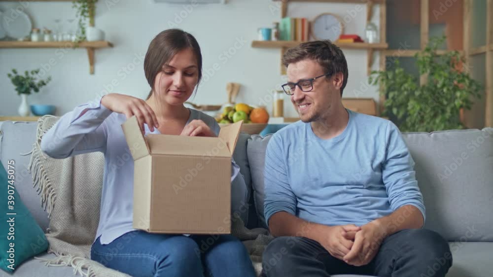 Ordering Gifts Online. A Man Gives a Woman a Gift that He Ordered Through the Site, an Online Store. The Girl Takes Out a Red Gift From a Cardboard Box. Happy Family Time. Enjoy Each Other. Ordering Gifts Online. A Man Gives a Woman a Gift that He Ordered Through the Site, an Online Store. The Girl Takes Out a Red Gift From a Cardboard Box. Happy Family Time. Enjoy Each Other.