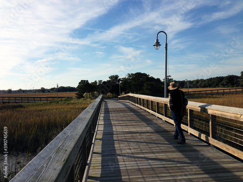 A man walking along the boardwalk over the salt marsh at Shem Creek, near Charleston, South Carolina, USA. photo