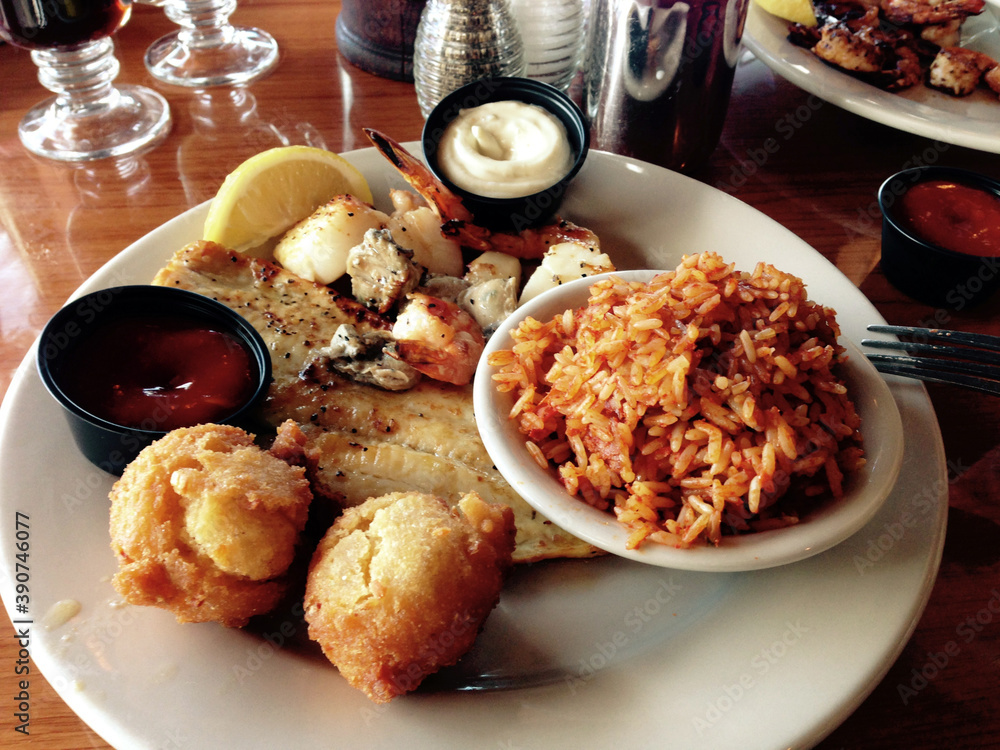 Fototapeta premium A southern seafood platter of grilled shrimp, fish and scallops with hushpuppies and red rice near Charleston, South Carolina, in the heart of the lowcountry.