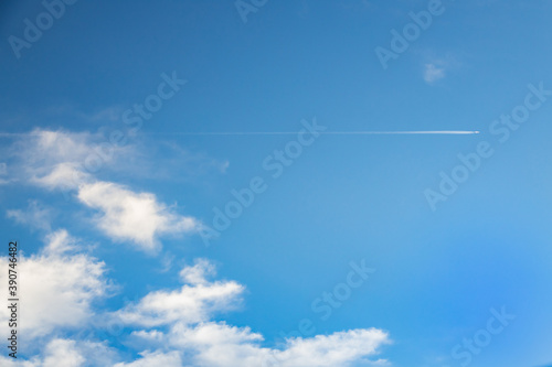 Blue sky, white clouds, airplane vapor trail
