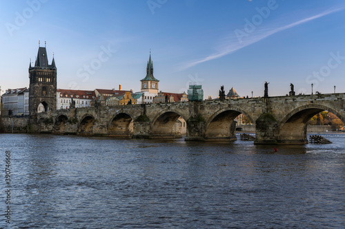 View of charles bridge and flowing river vltava in the center of prague at sunset the sky is blue in czech republic © svetjekolem