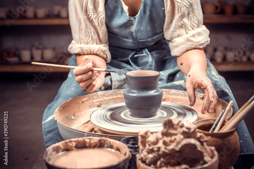 Pottery girl is working on pottery wheel. Folk handicraft. Close-up. photo