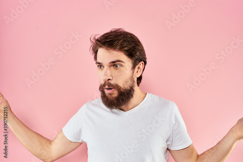 Man in white t-shirt gestures with hands emotions lifestyle cropped view pink background