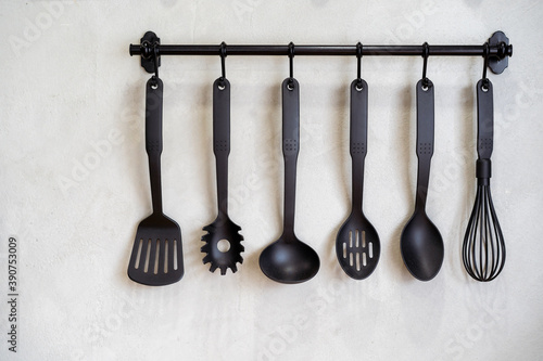 Modern kitchenware hanging on the wall rack close up. The professional kitchen tools decorate in kitchen.