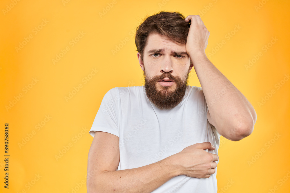 Man in white t-shirt emotions studio gestures with hands displeased facial expression yellow background Man in white t-shirt emotions studio gestures with hands displeased facial expression yellow background
