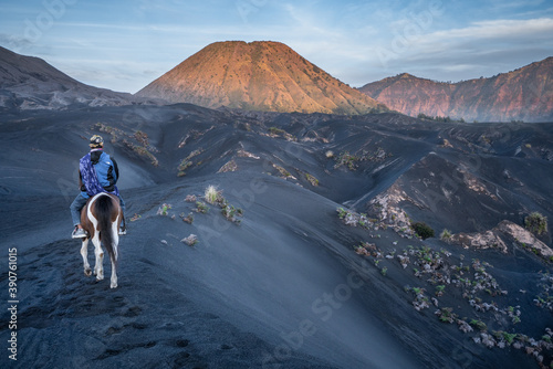 Bromo National Park, East Java, Indonesia - October 16, 2020 : Tengger man riding his horse on the black sand savanna of Mt Bromo, heading for Mt Batok