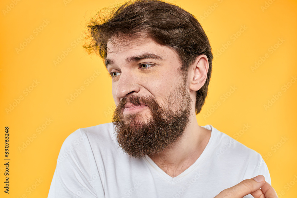 Obraz premium Man with emotional expression white t-shirt close-up studio yellow background