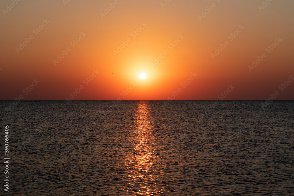Natural beautiful sunrise over sea and horizon in the morning. Sunlight reflected on calm waves. Seascape under scenic colorful sky sunrise
