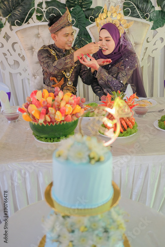 The bride couple  wearing Malay traditional  cloth  eats with their family or Makan Beradab  in wedding ceremony . Happy & Family Concept.