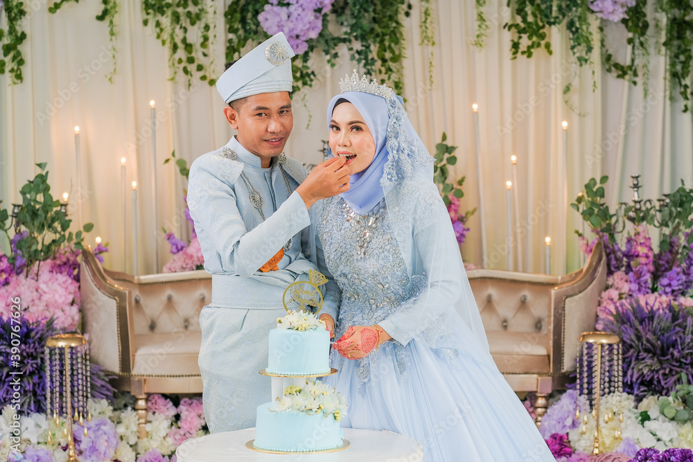 Malaysian wedding couple having a slice of cake after their reception event.