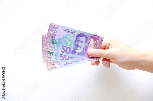 Closeup Dollar banknotes in male hand on a solid background, 50 NZ bills from New Zealand, held by a male hand on isolated white background, payday concept
