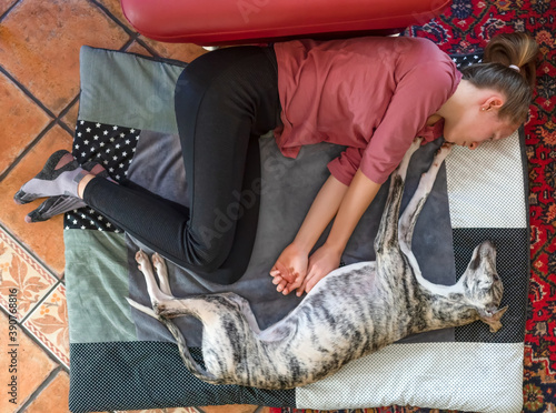 hübsche junge Frau schläft mit Ihrem Whippet Windhund auf  auf der Hundedecke am Boden vor der Couch