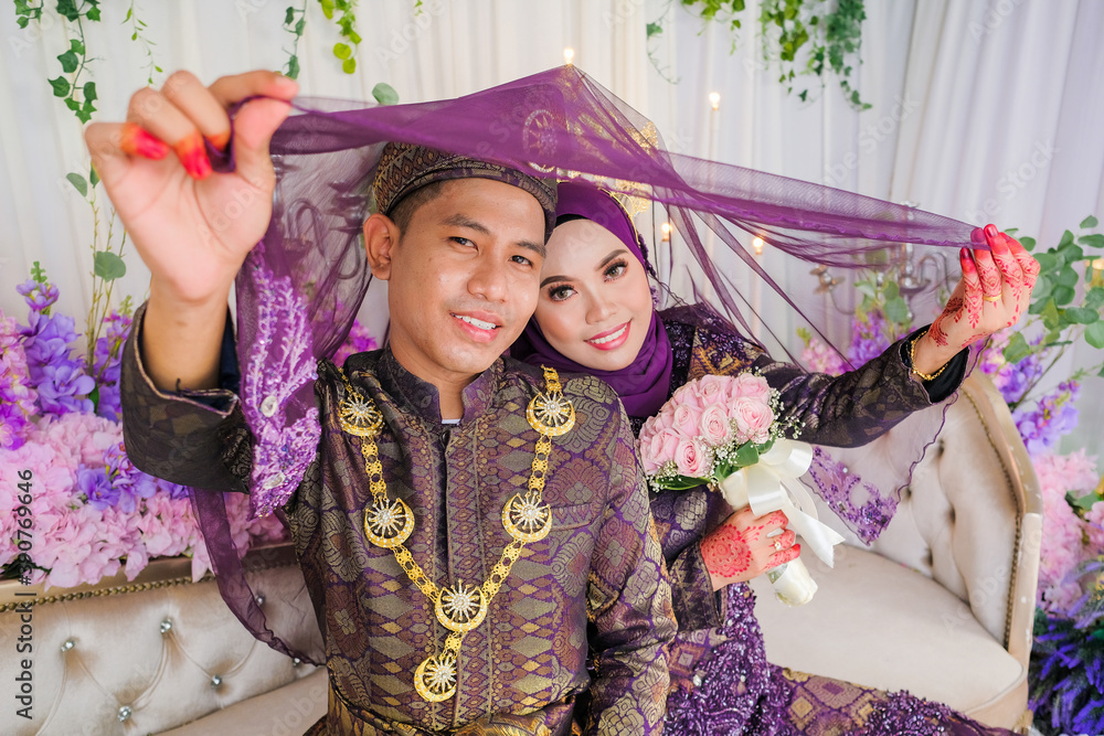 Fototapeta premium Indoor shooting for Malay wedding, the bride and groom wearing Malay traditional cloth in marriage ceremony . Happy & Family Concept.