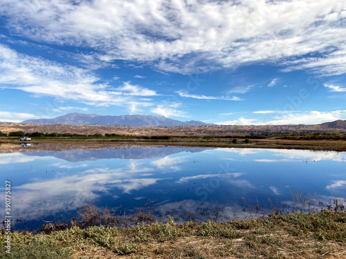Beautiful reflections of clouds and hills in a duck pond in San Jacinto Wildlife area near Perris, California on a blue sky day with awesome clouds. 