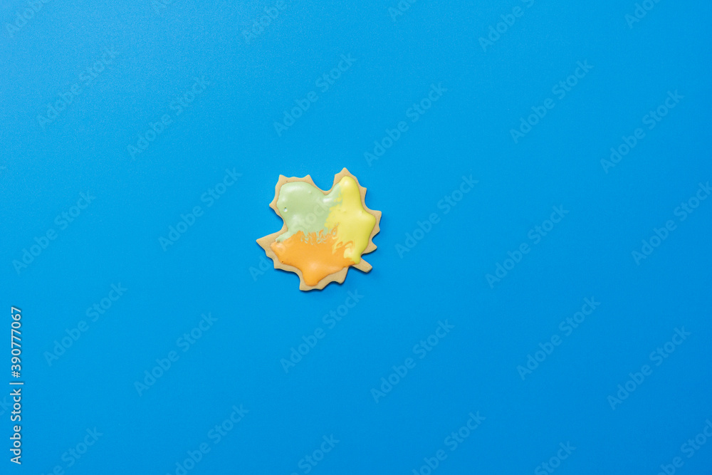 Sweet homemade leaf cookie with icing isolated on dark blue background minimal flat lay composition. Sweet homemade leaf cookie with icing isolated on dark blue background minimal flat lay composition.