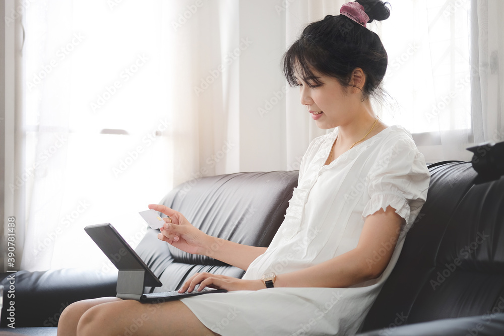 A young woman hand holding credit card and using computer laptop for online shopping at home. A young woman hand holding credit card and using computer laptop for online shopping at home.