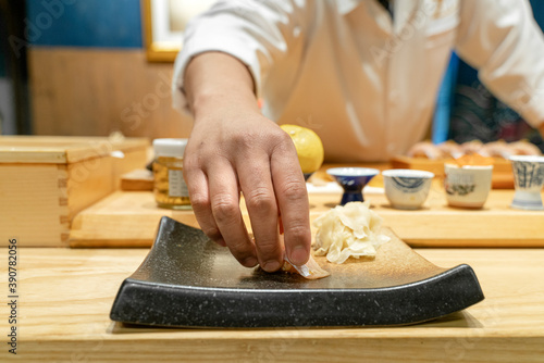 Japanese Sushi Chef serve sushi by hand on the black shimmer plate. (Omakase sushi course) Selective focus on sushi.