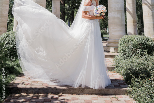 bride in wedding dress and bouquet in the park