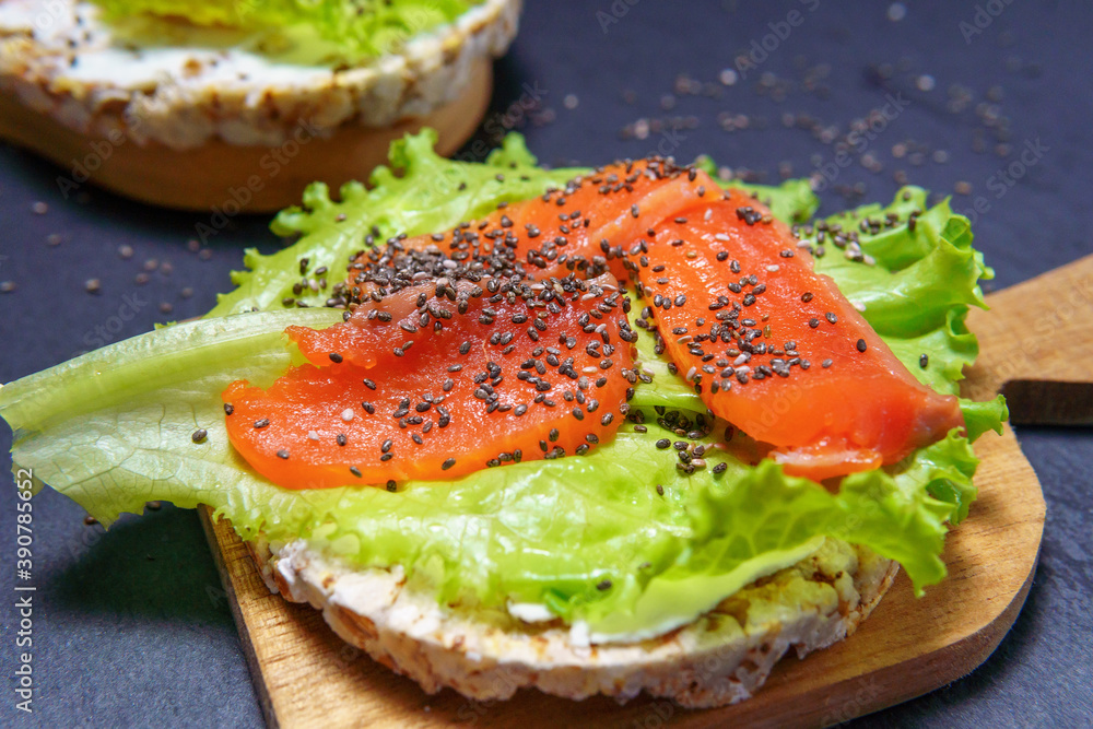Cheese and trout sandwich on a wooden Board. Diet Breakfast sandwich with red fish, lettuce, Chia seeds