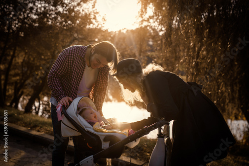 Young happy family is walking with their baby in a stroller in an autumn park.