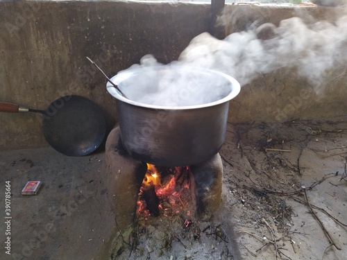 White smoke coming out from the pan. Cooking Rajasthani food on mud challah or stove or oven. photo