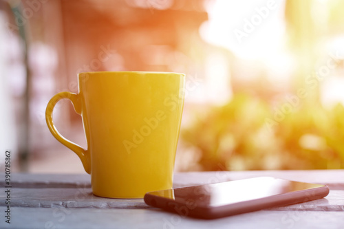 Yellow coffee cup over wooden table in front of autumnal background